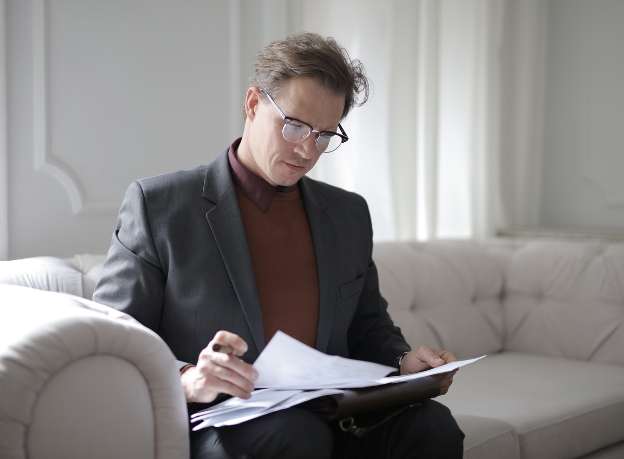 Image of a lawyer reading documents at Bickell & Mackenzie, Redland Bay, accompanying the article titled "Should People Sign Unconditional Contracts in Investments?"
